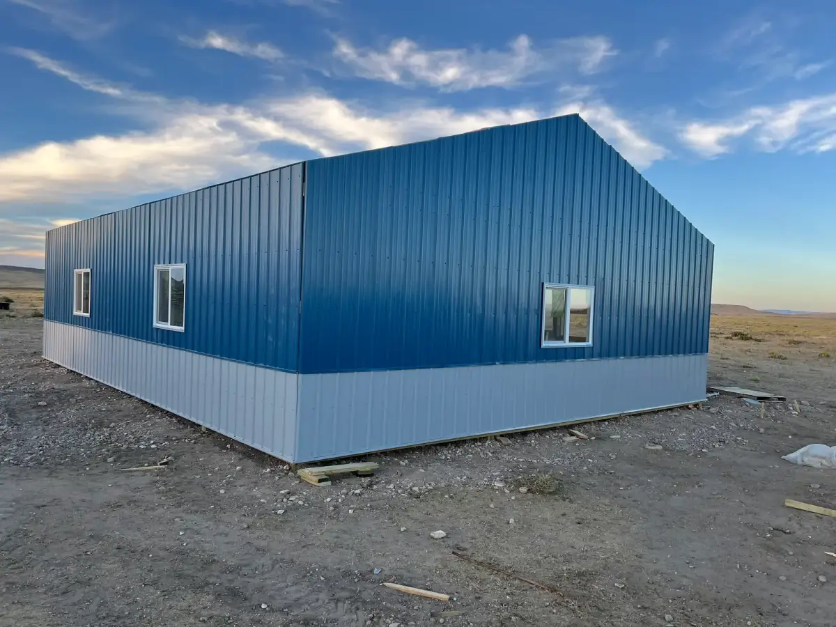 Blue metal-sided building with light-gray lower panels and white-framed windows.