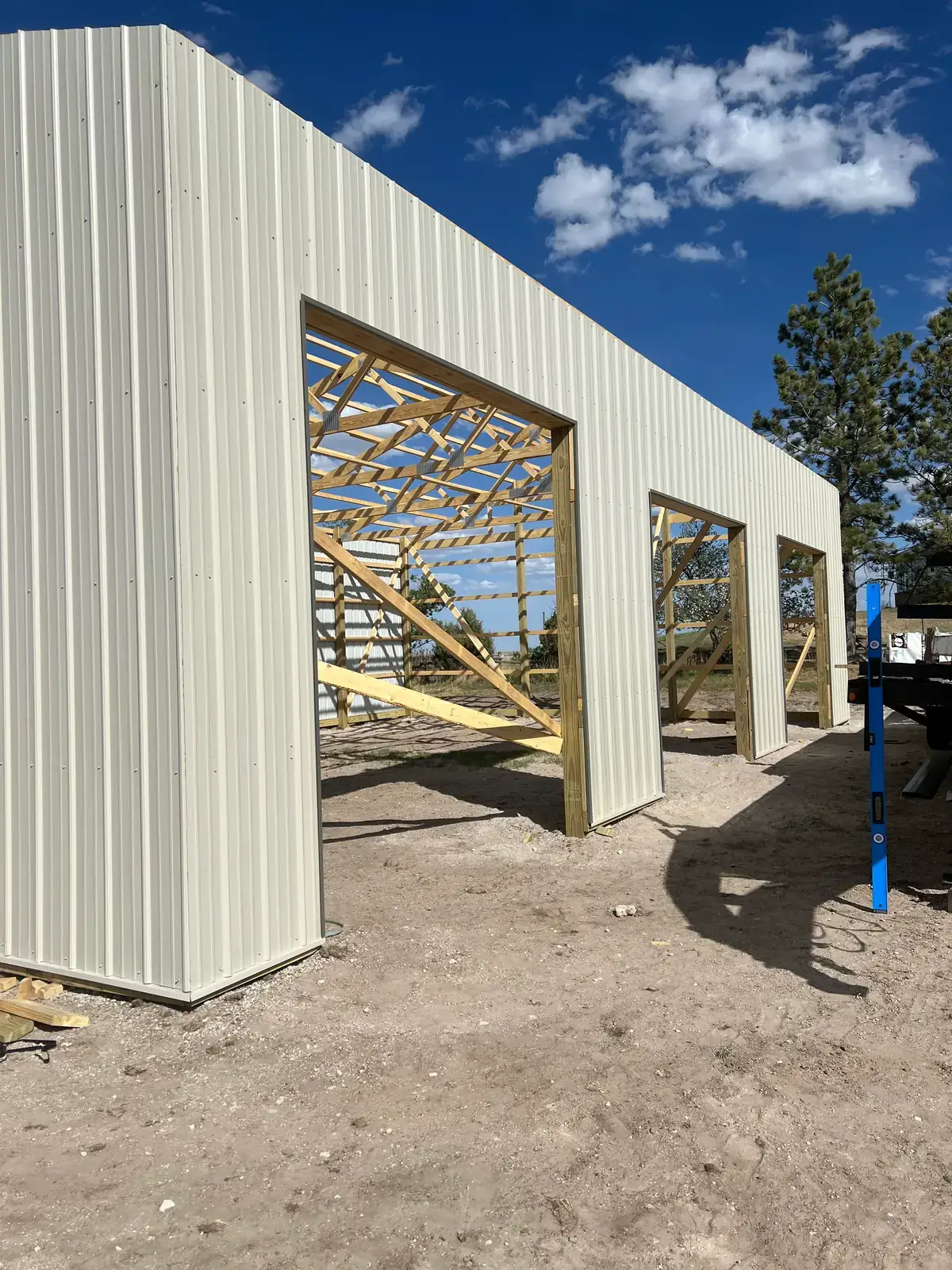 Light-colored metal siding surrounds large framed garage-door openings.