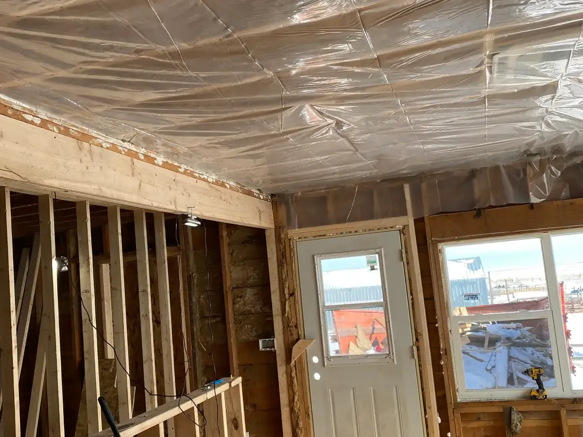 Exposed wall studs and insulation in the ceiling of a room under construction.