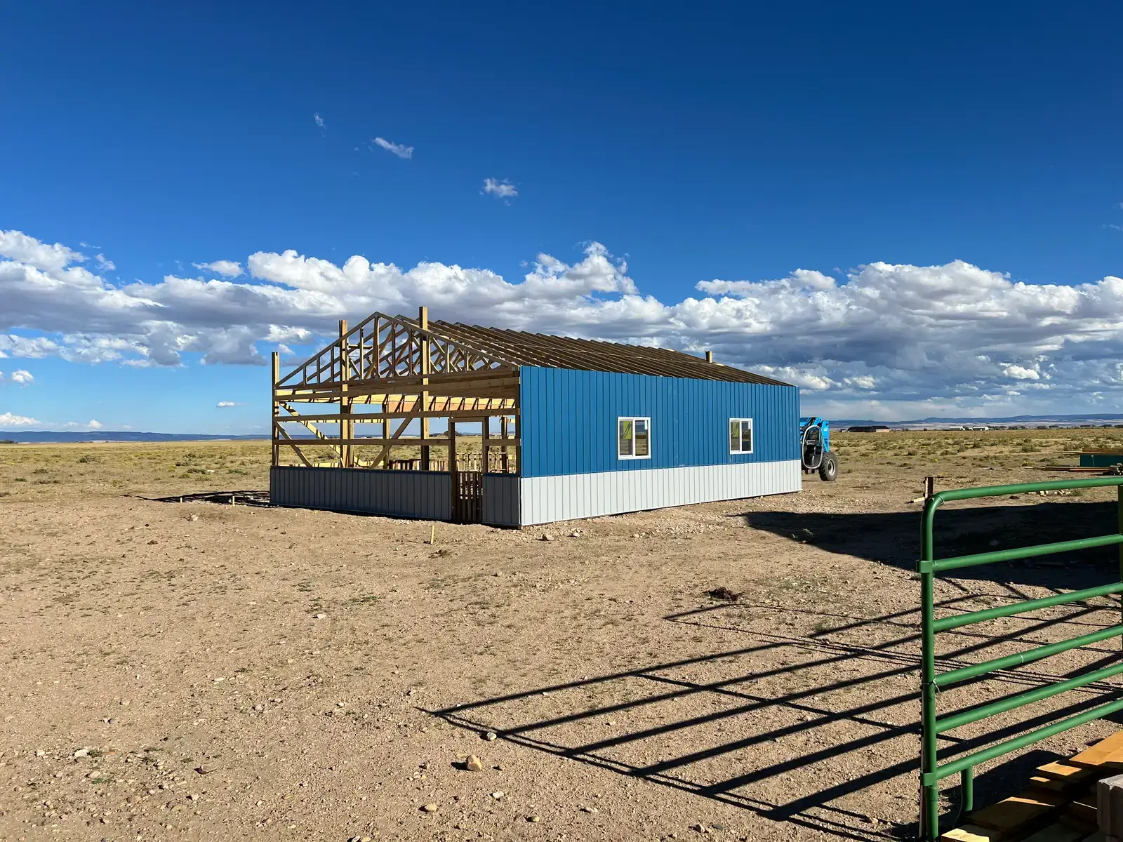 Blue metal siding covers one long wall while the front framing remains exposed.