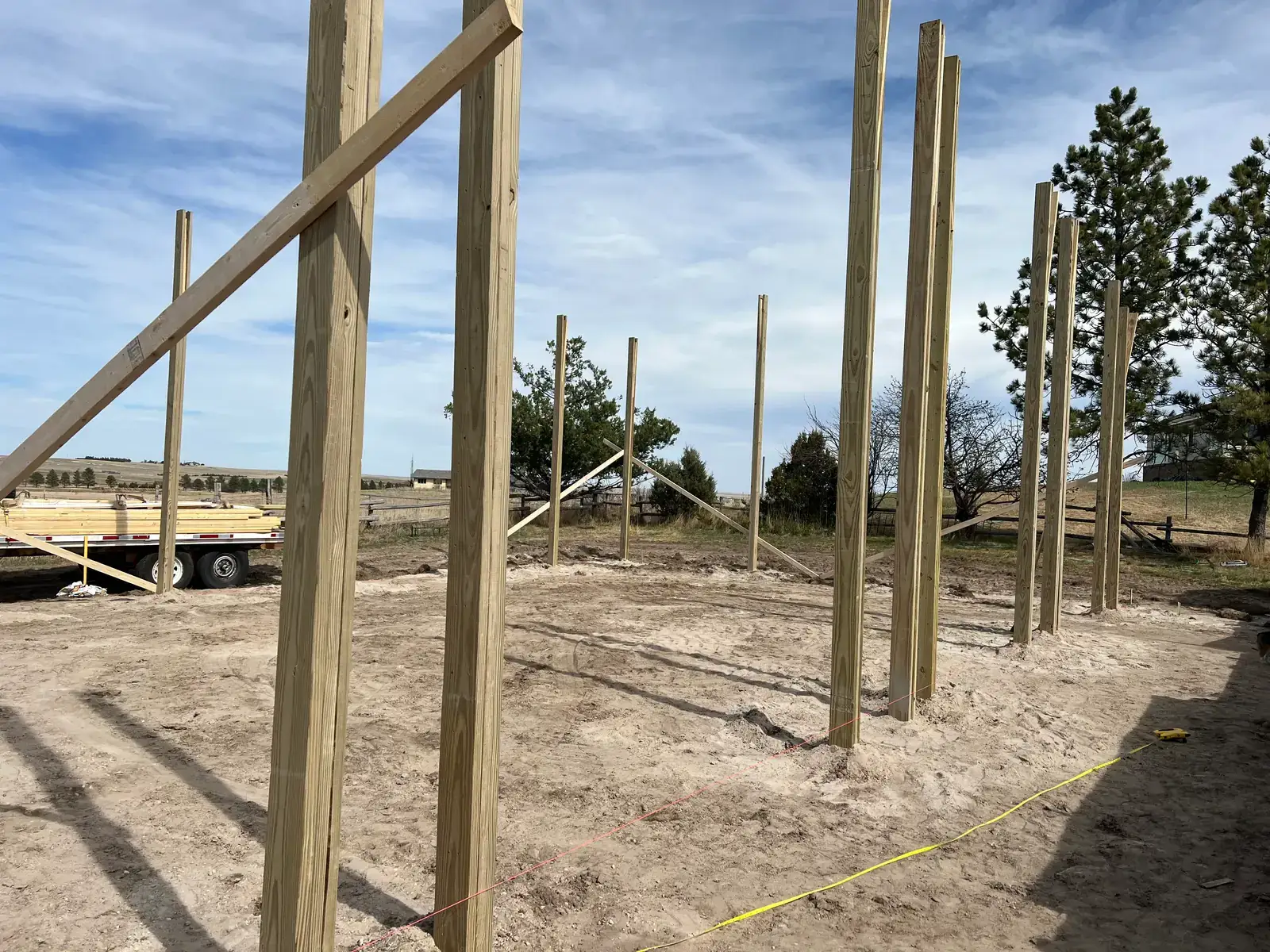 Upright timber posts with diagonal braces mark the edge of the garage footprint.