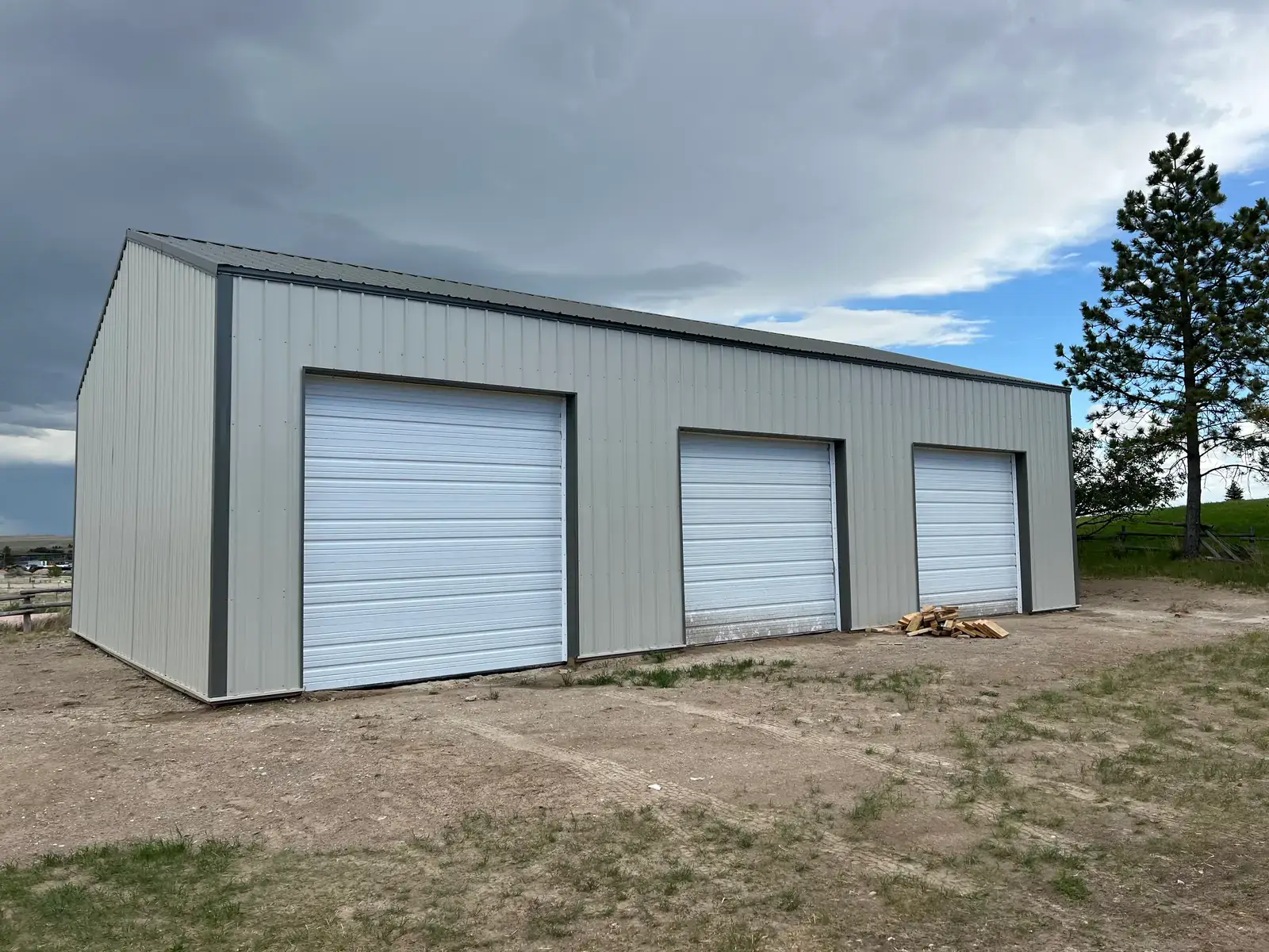 Metal garage with three closed white overhead doors and contrasting dark trim.